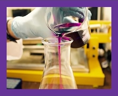 A person pouring purple liquid into a beaker